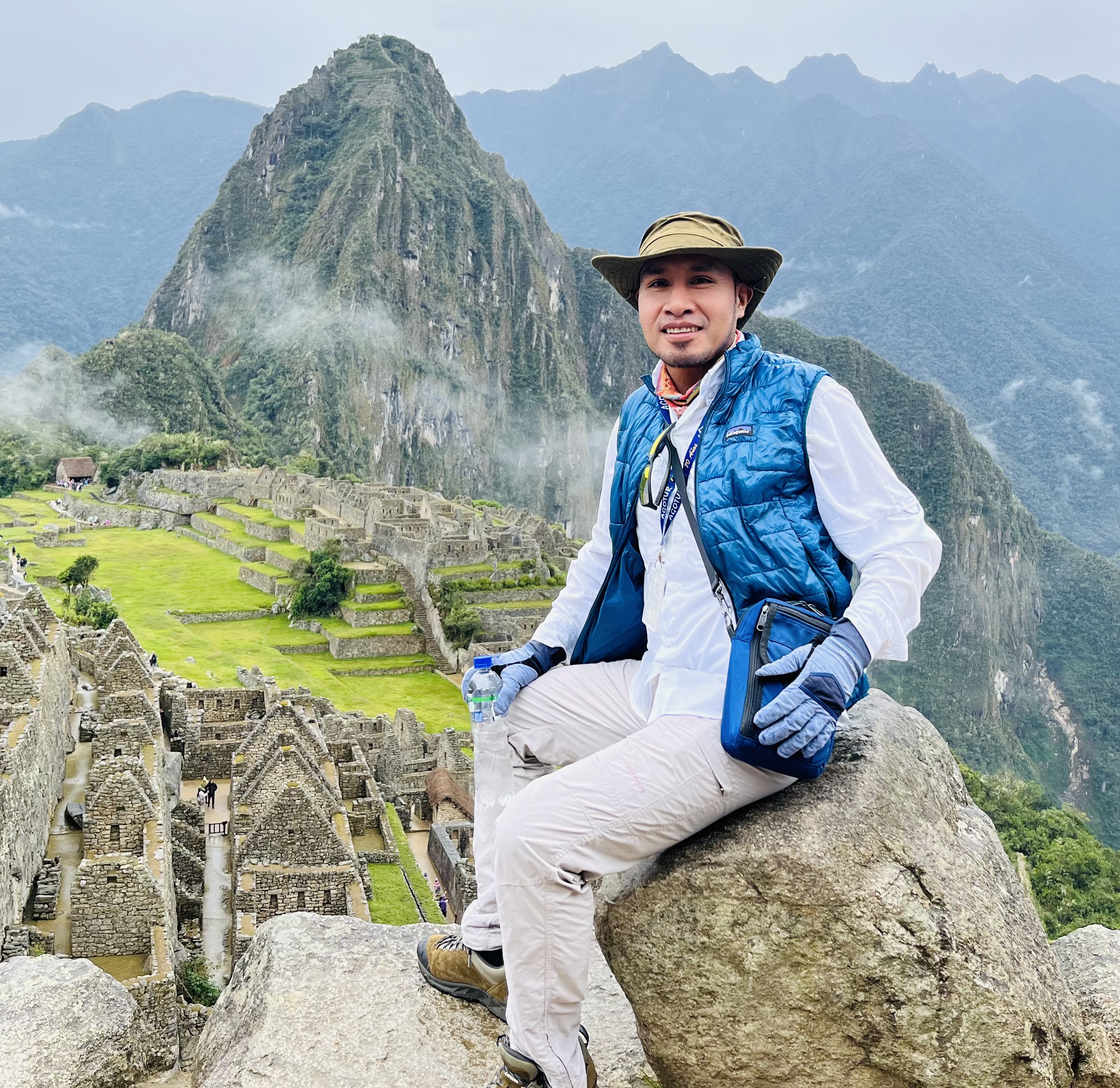 a man sitting on a rock with a stone structure in the background